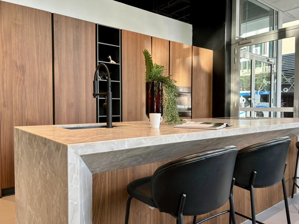 Luxury modern kitchen design with fluted timber panels, marble waterfall island, black tapware and bar seating