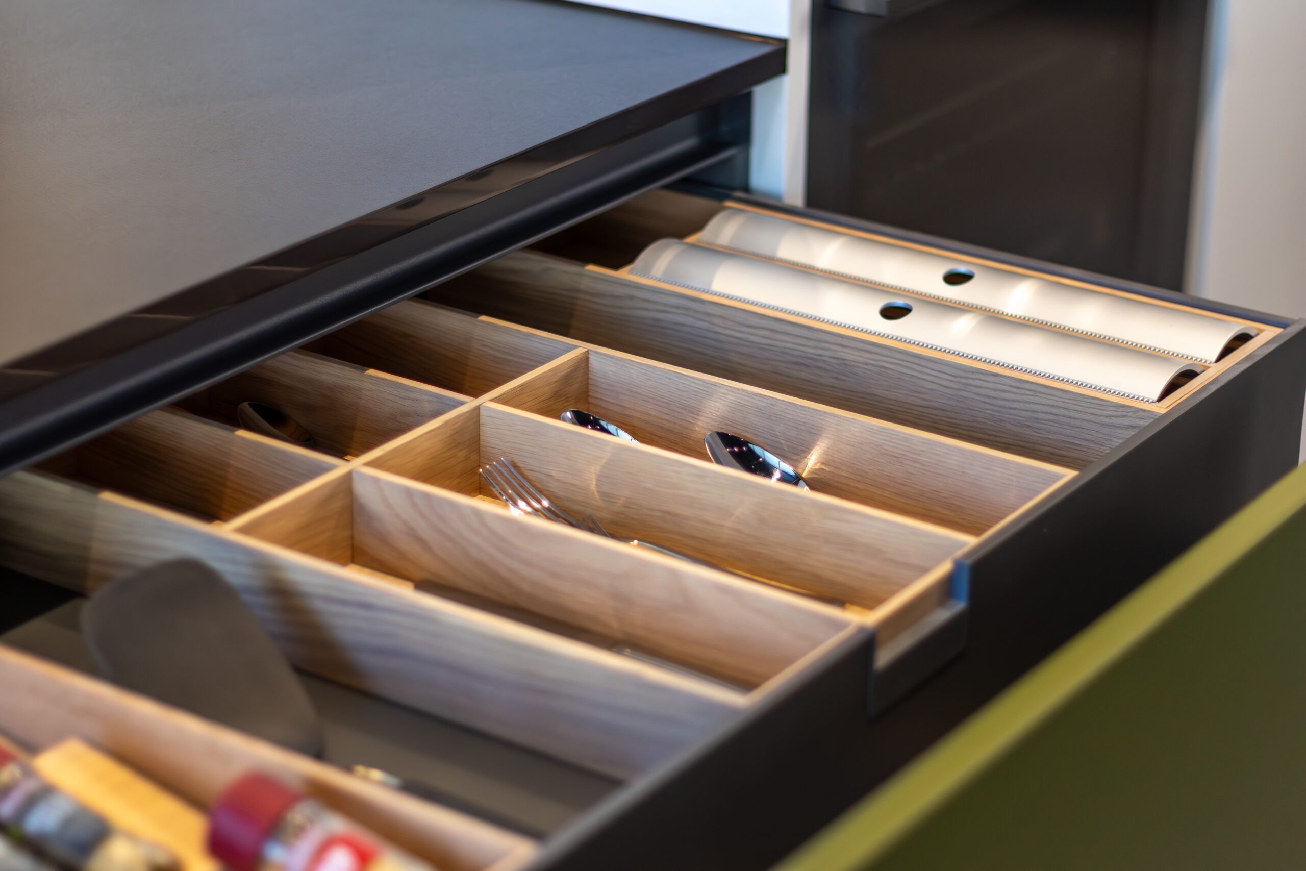 Open kitchen drawer with wooden cutlery organiser and utensils