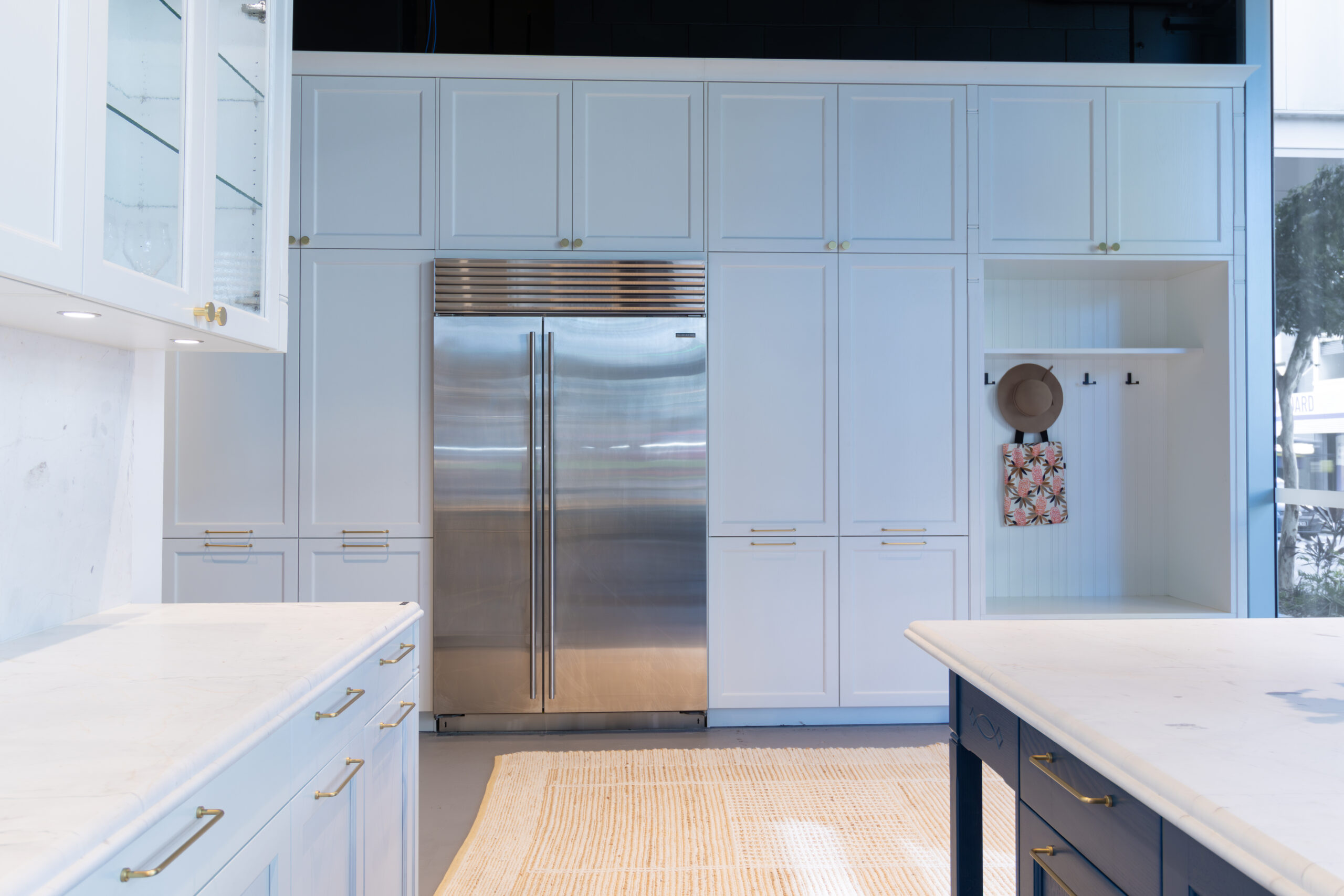 Bright kitchen with white cabinetry and stainless steel fridge