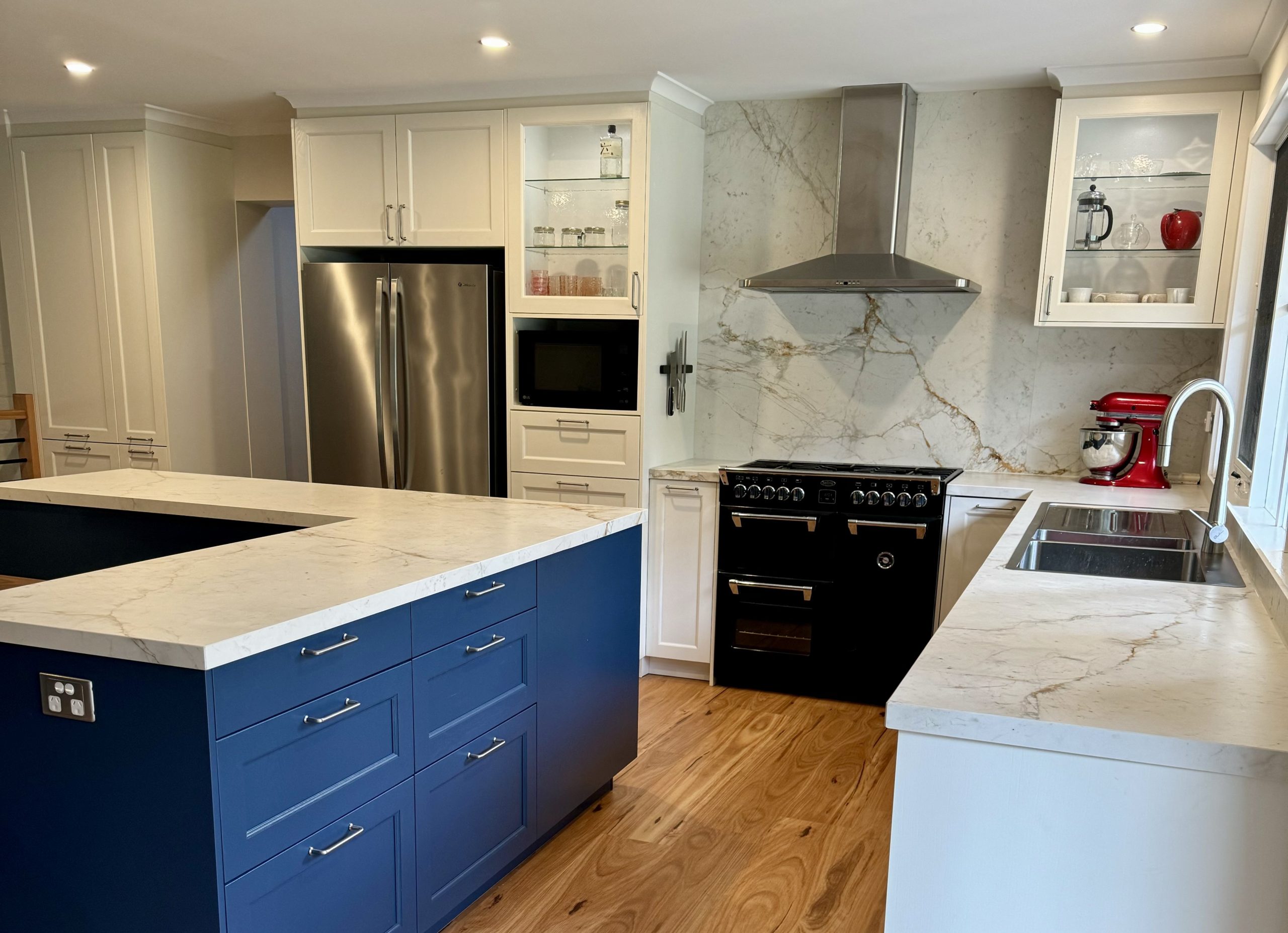 Bespoke Häcker luxury kitchen with marble stone benchtop and splashback, large l-shaped kitchen island, premium navy blue kitchen cabinetry.