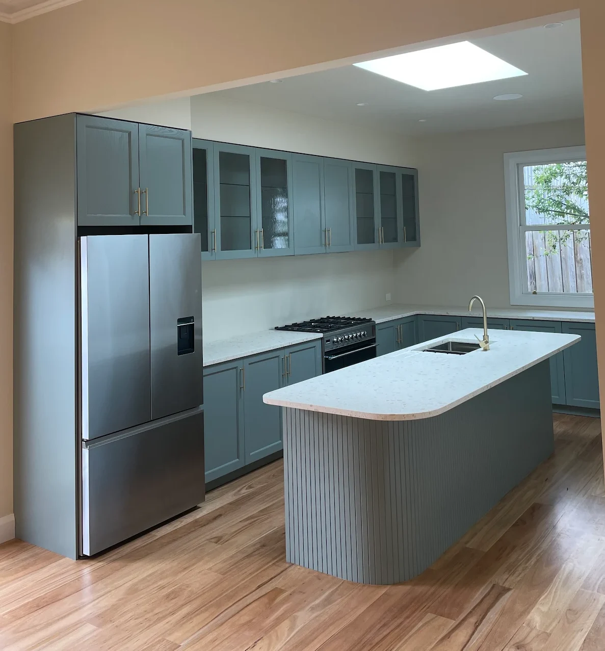 Luxury Häcker kitchen with rounded and fluted kitchen island and eucalyptus green premium cabinetry